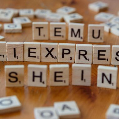 Wooden Scrabble tiles display popular e-commerce platforms on a wooden surface.